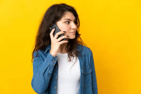 Teenager Russian Girl Isolated Yellow Background Keeping Conversation Mobile Phone — стоковое фото