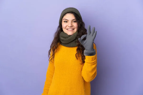 俄罗斯少女 头戴冬季帽子 背景为紫色 手部有明显的标志 — 图库照片