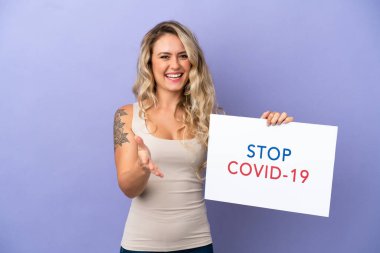 Mor arka planda izole edilmiş genç Brezilyalı bir kadın elinde yazılı bir levhayla Covid 19 'u durdurun bir anlaşma yapıyor.