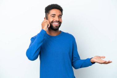 Beyaz arka planda izole edilmiş genç Brezilyalı bir adam cep telefonuyla sohbet ediyor.