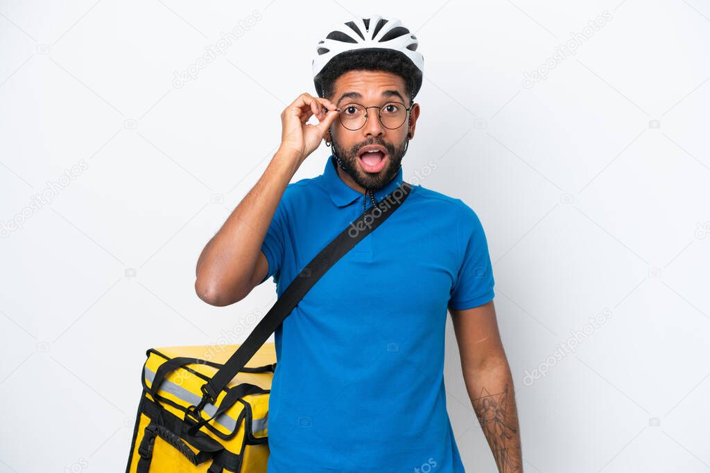 Young Brazilian man with thermal backpack isolated on white background with glasses and surprised
