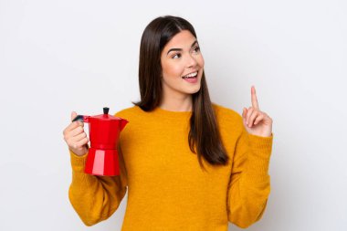 Beyaz arka planda kahve demliği tutan genç Brezilyalı kadın çözümü fark etmek için parmağını kaldırıyor.