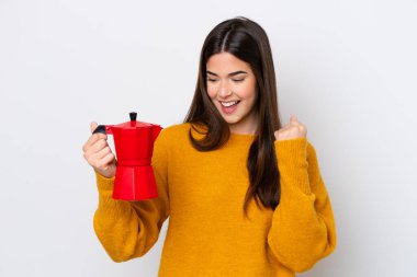 Genç Brezilyalı kadın elinde kahve makinesiyle beyaz arka planda zaferi kutluyor.