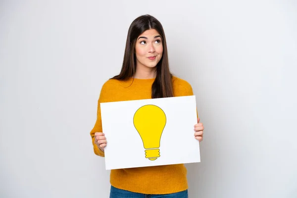 Young Brazilian Woman Isolated White Background Holding Placard Bulb Icon — Stock Photo, Image