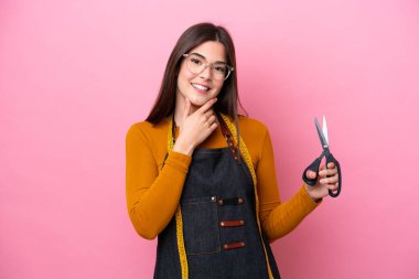 Genç Brezilyalı terzi kadın pembe arka planda yalnız mutlu ve gülümsüyor.