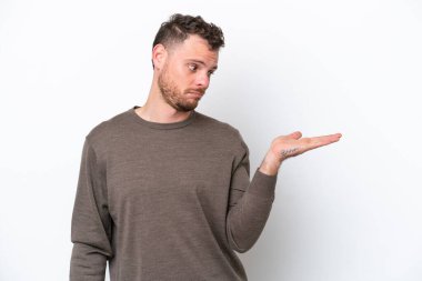 Beyaz arka planda izole edilmiş genç Brezilyalı adam, kopyalama alanını şüphe ile tutuyor