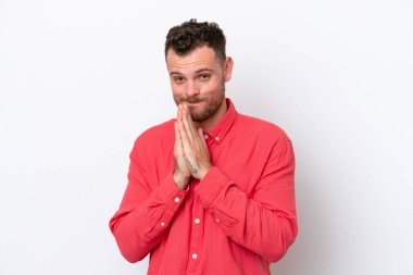 Beyaz arka planda izole edilmiş genç Brezilyalı adam avuç içlerini bir arada tutuyor. İnsan bir şey ister.