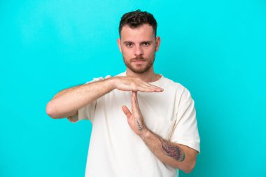 Genç Brezilyalı bir adam mavi arka planda izole edilmiş.