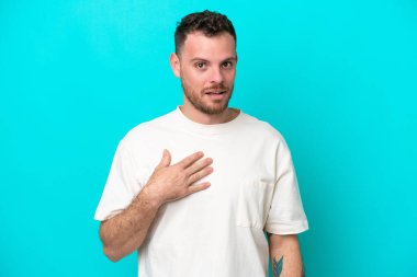 Mavi arka planda izole edilmiş genç Brezilyalı adam kendini işaret ediyor.