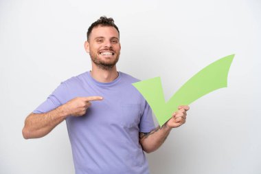 Beyaz arka planda izole edilmiş genç Brezilyalı bir adam elinde bir çek simgesi tutuyor ve onu işaret ediyor.