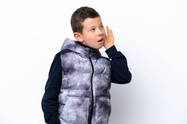 Beyaz arka planda izole edilmiş küçük bir çocuk bir şeyler dinlerken elini kulağına koyar.