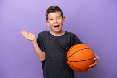 Basketbol oynayan küçük çocuk, mor arka planda şok olmuş yüz ifadesiyle izole edilmiş.