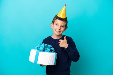 Küçük çocuk mavi arka planda izole edilmiş doğum günü pastası tutuyor.