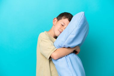 Mavi arka planda pijamalı küçük bir çocuk.