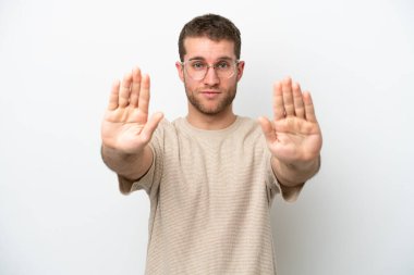 Beyaz arka planda izole edilmiş genç beyaz adam dur hareketi yapıyor ve hayal kırıklığına uğruyor.