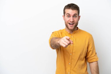 Beyaz arka planda izole edilmiş genç beyaz adam şaşırmış ve ön tarafı işaret ediyor.