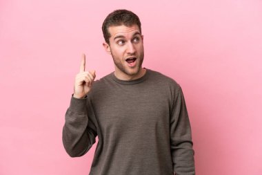 Pembe arka planda izole edilmiş genç beyaz adam çözümü bulmak için parmağını kaldırıyor.