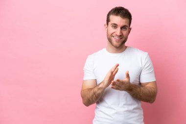 Pembe arka planda izole edilmiş genç beyaz adam bir konferanstan sonra alkışlıyor.