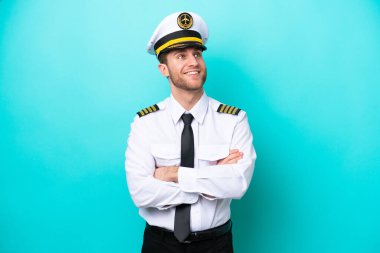 Kafkasyalı pilot mavi arka planda izole edilmiş mutlu ve gülümsüyor.