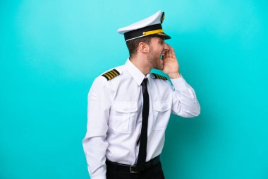 Kafkasyalı uçak pilotu mavi arka planda izole edilmiş ve ağzı sonuna kadar açık bağırıyor.