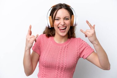 Beyaz arka planda izole edilmiş genç beyaz kadın rock hareketleri yapan müzik dinliyor.