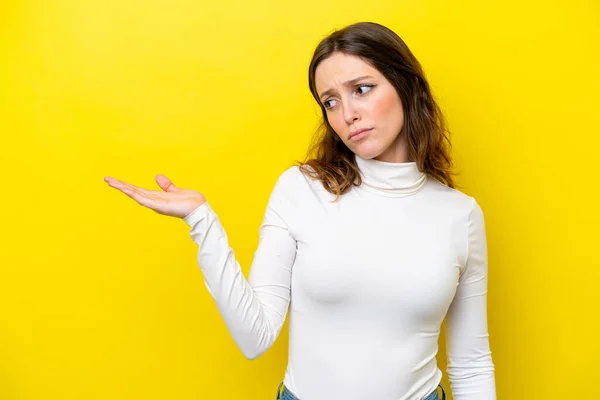 Mulher Caucasiana Jovem Isolado Fundo Amarelo Segurando Espaço Com Dúvidas — Fotografia de Stock