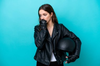 Motosiklet kasklı beyaz bir kadın mavi arka planda izole edilmiş. Şüpheleri var.