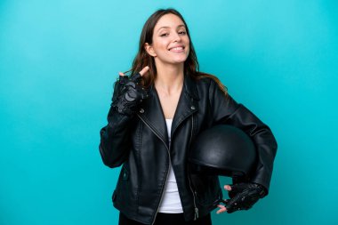 Mavi arka planda izole edilmiş motosiklet kasklı beyaz bir kadın baş parmak işareti yapıyor.