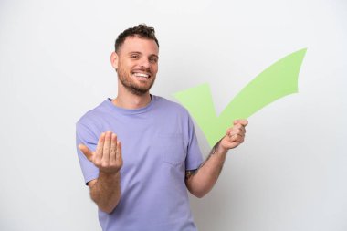 Beyaz arka planda izole edilmiş genç Brezilyalı bir adam elinde bir çek ikonu tutuyor ve gelecek jestler yapıyor.