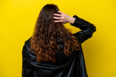 Genç beyaz kadın sarı arka planda izole edilmiş ve düşünüyor.