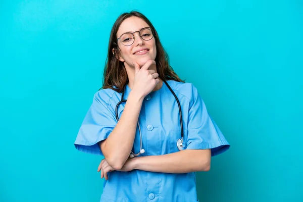 年轻的外科医生女医生在蓝色背景上孤立无援 笑容满面 — 图库照片