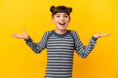 Küçük beyaz kız sarı arka planda izole edilmiş ve şok olmuş yüz ifadesi var.