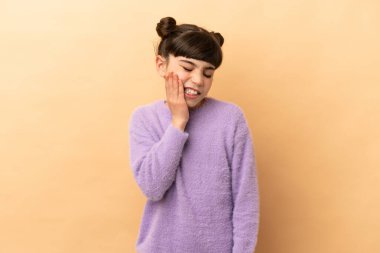 Bej arka planda izole edilmiş diş ağrısı olan beyaz bir kız.