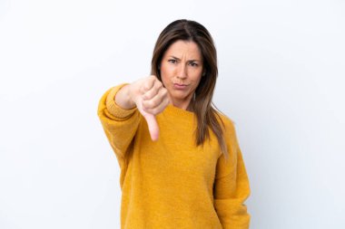 Beyaz arka planda izole edilmiş orta yaşlı beyaz kadın olumsuz ifadeyle baş parmağını aşağı gösteriyor.