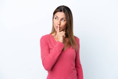 Beyaz arka planda izole edilmiş orta yaşlı beyaz kadın parmağını ağzına koyan sessizlik işareti gösteriyor.