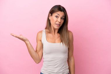 Pembe arka planda izole edilmiş orta yaşlı beyaz kadın şüpheli hareketler yapıyor.