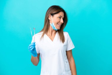 Mavi arka planda izole edilmiş orta yaşlı doktor kadın.