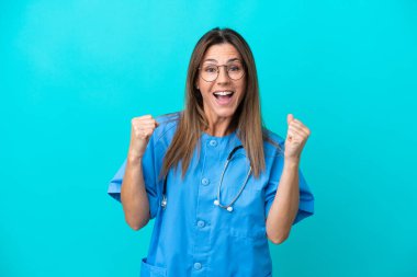 Orta yaşlı cerrah kadın mavi arka planda tek başına zaferi kutluyor.