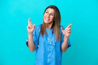 Orta yaşlı cerrah kadın mavi arka planda izole edilmiş ve şans diliyor.