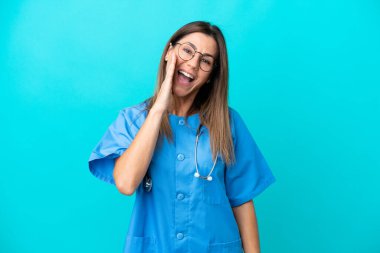 Orta yaşlı cerrah kadın mavi arka planda izole edilmiş ve ağzı açık bağırıyor.