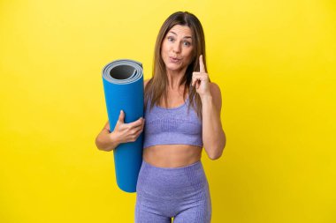 Spor kadını, elinde paspas tutarken yoga derslerine gidiyor. Sarı olmayan bir zemin tutuyor. Çözümün farkına varmak için parmağını kaldırıyor.