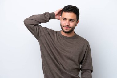 Genç Brezilyalı bir adam beyaz arka planda izole edilmiş, kafası kaşınırken şüpheleri var.