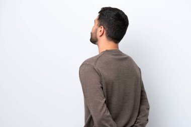 Genç Brezilyalı adam beyaz arka planda izole edilmiş ve arkasına bakıyor.
