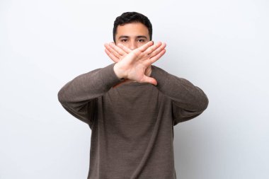 Genç Brezilyalı bir adam beyaz arka planda izole edilmiş bir şekilde bir eylemi durdurmak için el hareketi yapıyor.