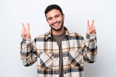 Beyaz arka planda izole edilmiş genç Brezilyalı iki eliyle zafer işareti gösteriyor.