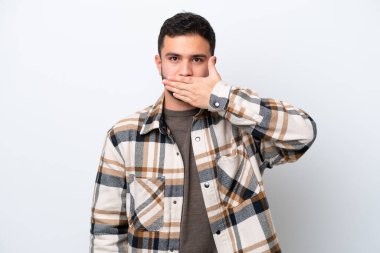 Genç Brezilyalı adam beyaz arka planda izole edilmiş, ağzı eliyle kapatıyor.