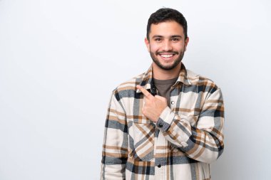 Beyaz arka planda izole edilmiş genç Brezilyalı bir adam bir ürün sunmak için kenarı işaret ediyor