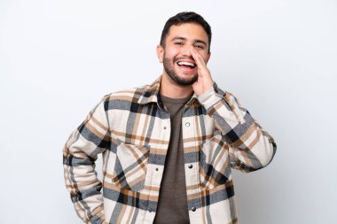 Beyaz arka planda izole edilmiş genç Brezilyalı adam ağzı açık bağırıyor.