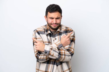 Beyaz arka planda izole edilmiş genç Brezilyalı adam, yan taraftakilerin şüphelerine işaret ediyor.