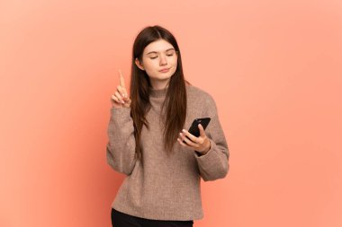 Genç Ukraynalı kız pembe arka planda cep telefonu ve parmak kaldırarak izole edilmiş.